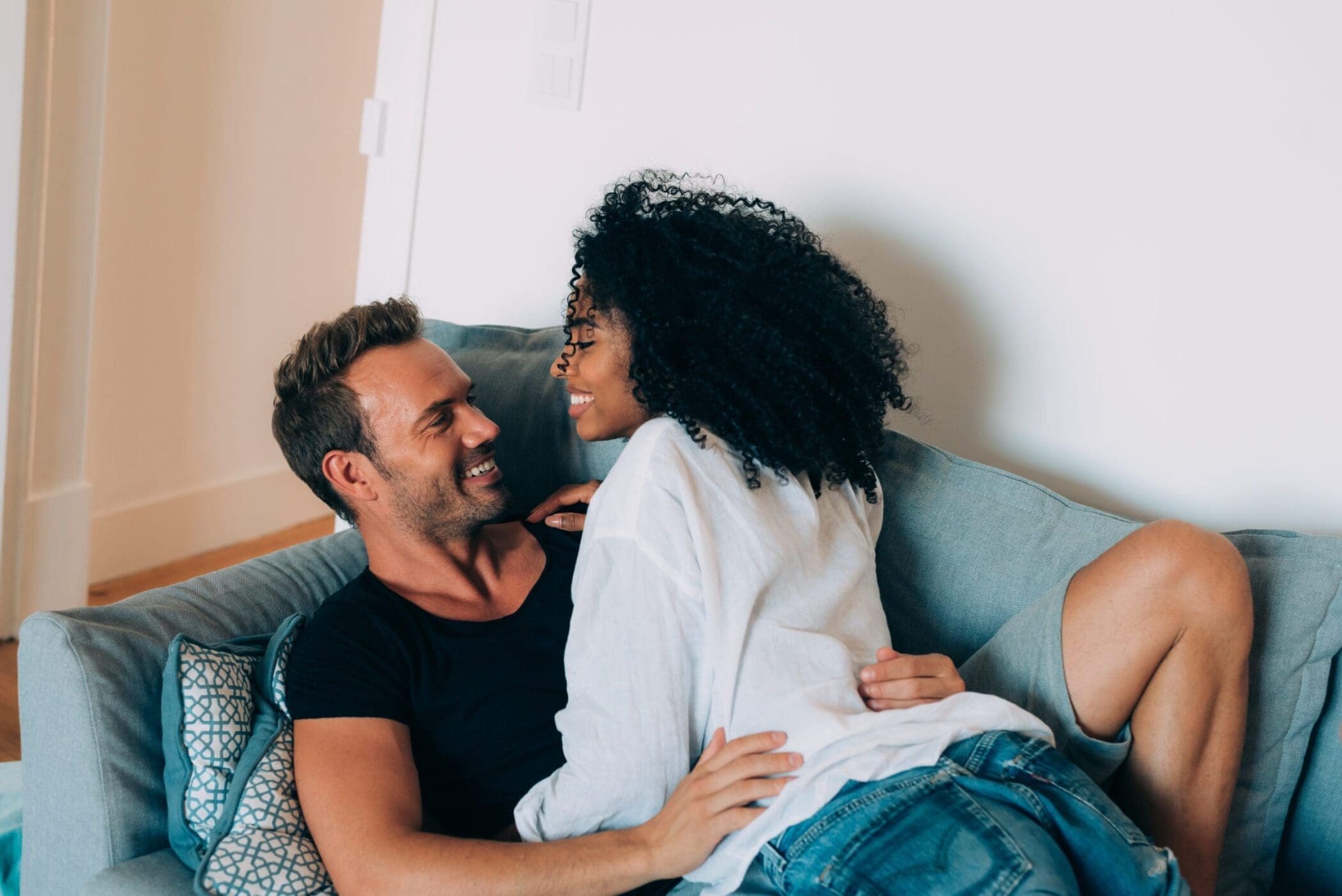 Happy young couple relaxed at home in the couch having fun playing with each other