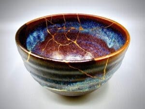 A rainbow colored pottery bowl glued back together after coming apart. 