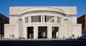 Picture of the front of the United States Holocaust Memorial Museum with a stone, grey rounded front with pillars.
