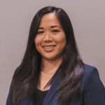 Professional portrait of Philadelphia Psychiatrist and Therapist Dr. Jennifer Trinh. She is looking directly at the camera and is wearing a dark blue blazer. She is against a blank grey wall.